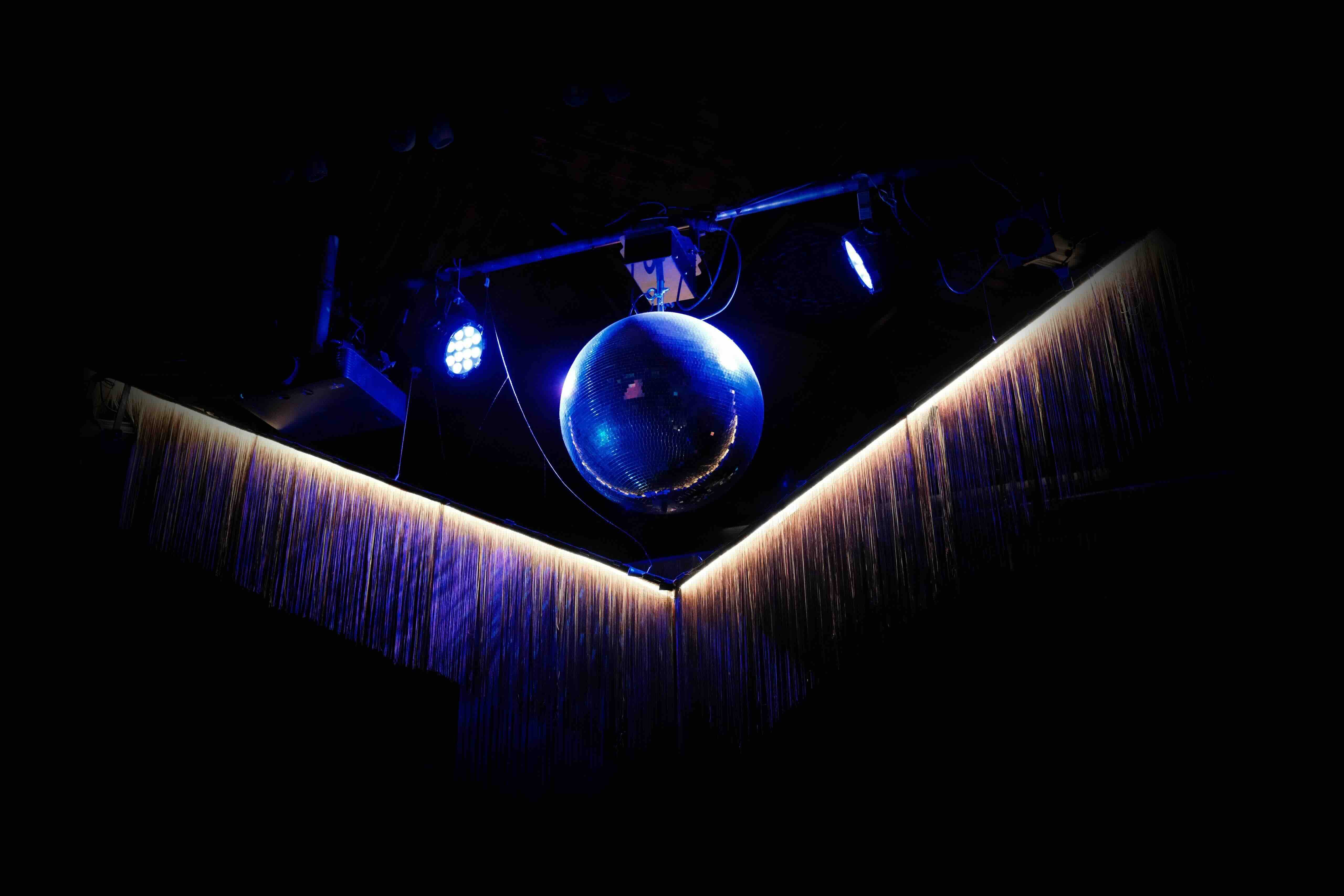 An illuminated disco ball surrounded by fabric fringing
